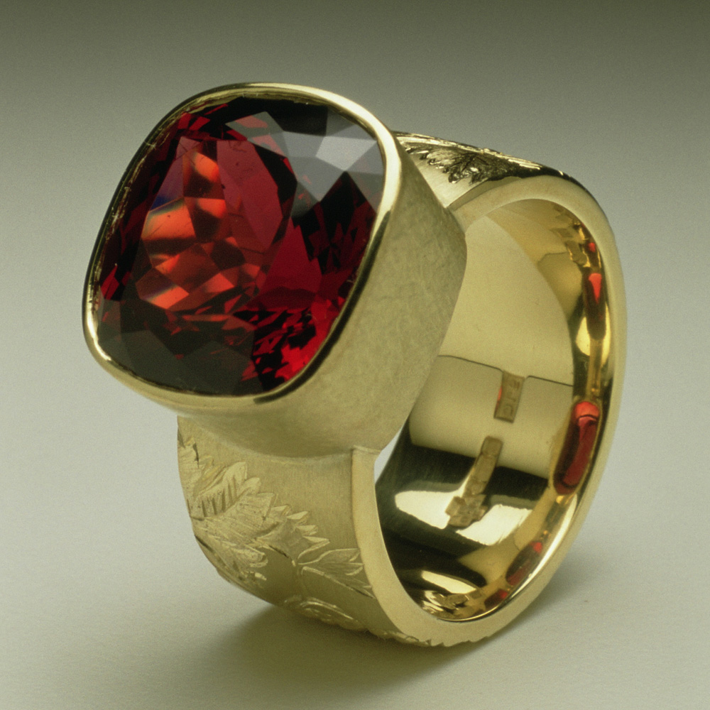 18ct yellow gold, hand engraved and carved with vine leaves and grapes, cushion cut garnet. 