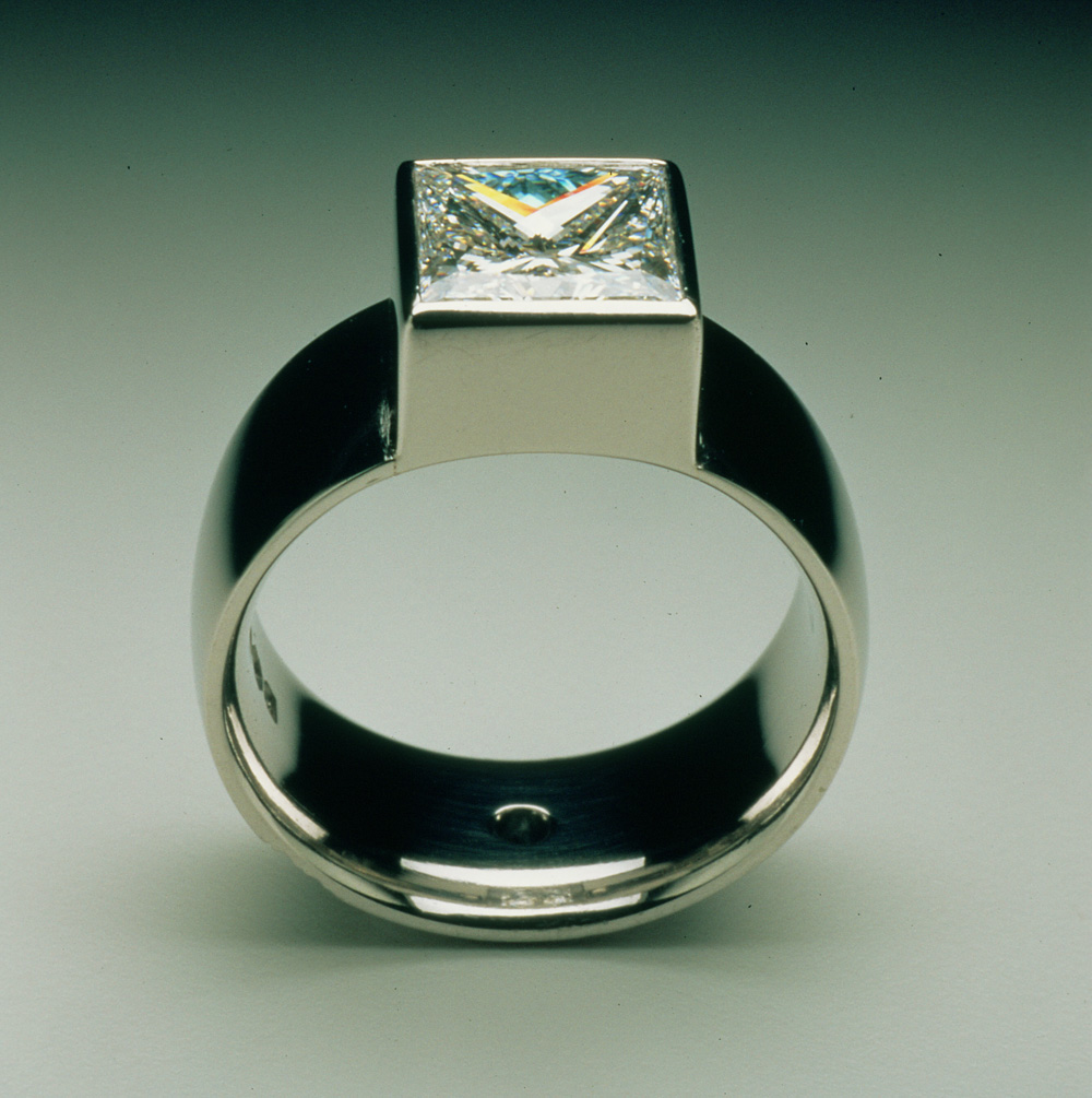 Square diamond set in platinum, small blue diamond in centre of back of the shank.