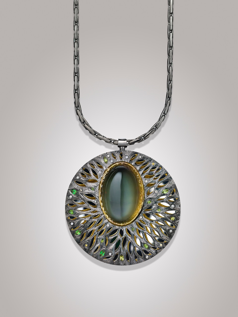 Silver, hand engraved and pierced with moonstone set in green gold, with green tourmalines and grey diamonds. (Commission)