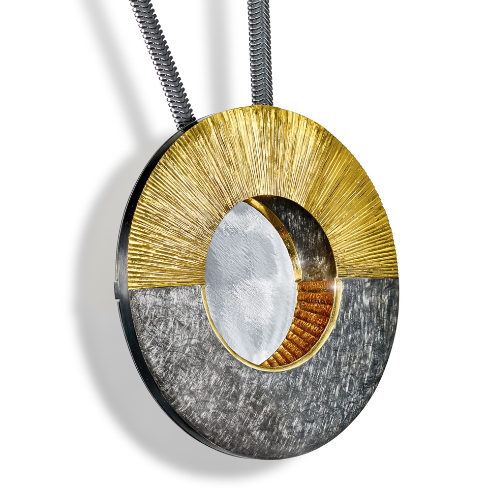 Part hand engraved part scrubbed finish. Rhodium plated in dark grey and part gilded. 5.7 cm diameter.