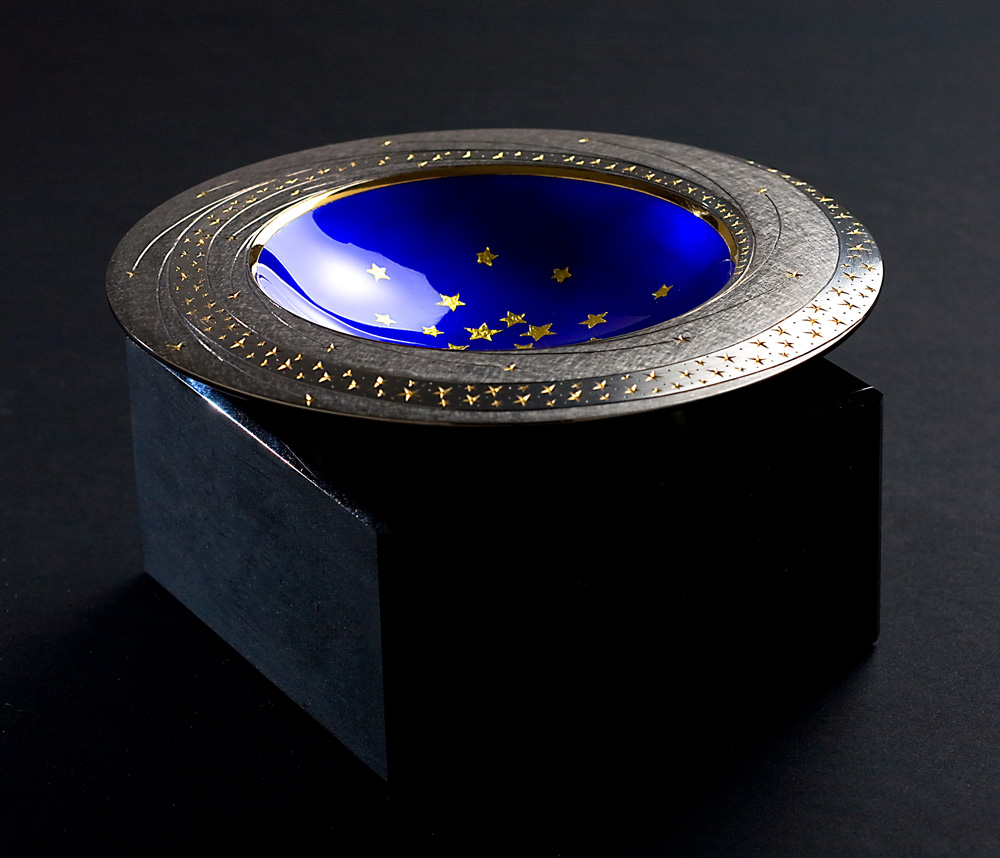 Angle view: Star Bowl 2008/9. 150 mm diameter. Base Black Obsidian. Bowl - Silver, yellow and black gilding, hand engraved, blue enamel, gold leaf stars. Photo : Simon Armitt.