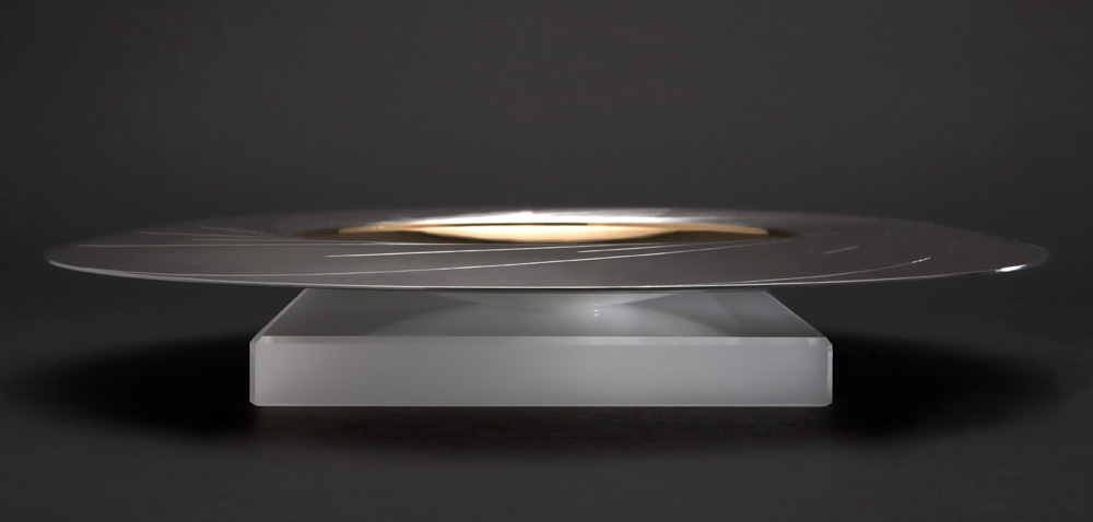 Side view: "SUN DISH" 300 mm diam. Silver, hand engraved. Center yellow gilded. Stone Base - Optical Quartz. Photo : Simon Armitt