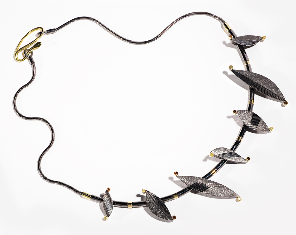 Silver, black rhodium plated, 18ct gold details, set with natural yellow and treated orange diamonds. Photo: Simon Armitt.
