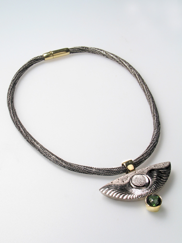 18ct white gold ,carved and engraved drop with 18ct yellow gold, cushion cut pale green tourmaline in 18ct yellow gold setting. Chain: oxidised silver with 18ct yellow gold clasp.Photo: Andra Nelki