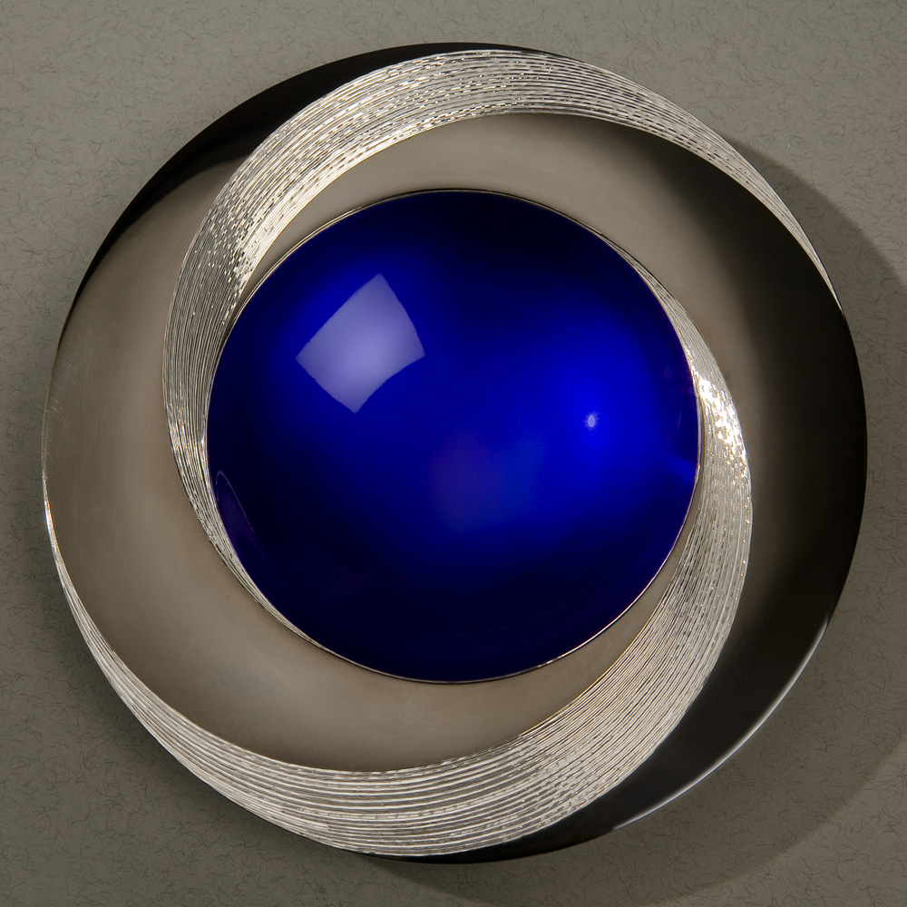 BLUE INFINITY BOWL 150 mm diameter. Britannia Silver. Blue Enamel, Black Gilding, Hand Engraved. Base frosted and polished Optical Quartz. Bowl is designed to spin gently on its stone base. Photo : Simon Armitt