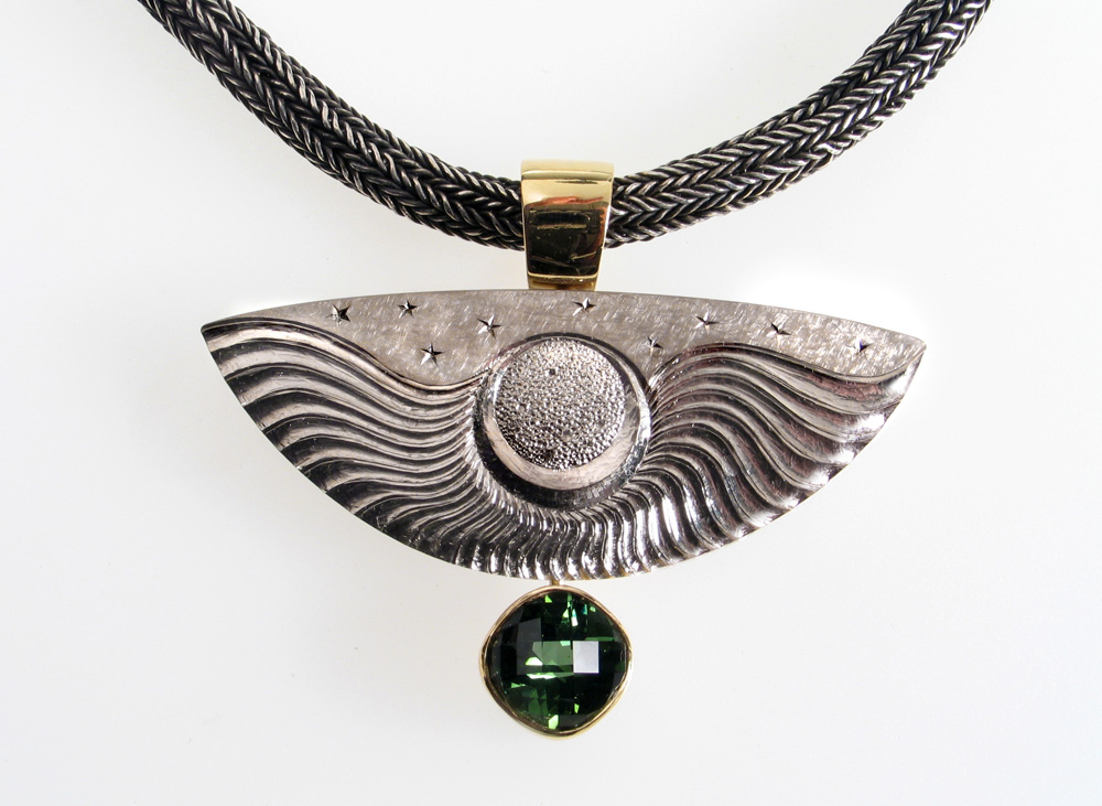 18ct white gold, carved and engraved drop with 18ct yellow gold, set with cushion cut pale green tourmaline in 18ct yellow gold setting. Chain: oxidised silver with 18ct yellow gold clasp.Photo: Andra Nelki