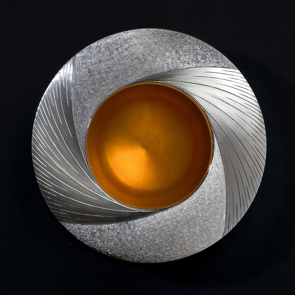 <a href="/jewellery/midday-bowl-commission-piece-2009-110-mm-diam-silver-hand-engraved-yellow-orange-enamel">Midday Bowl Commission piece 2009. 110 mm diam. Silver, hand engraved, yellow / orange enamel. Photo : Simon Armitt</a>