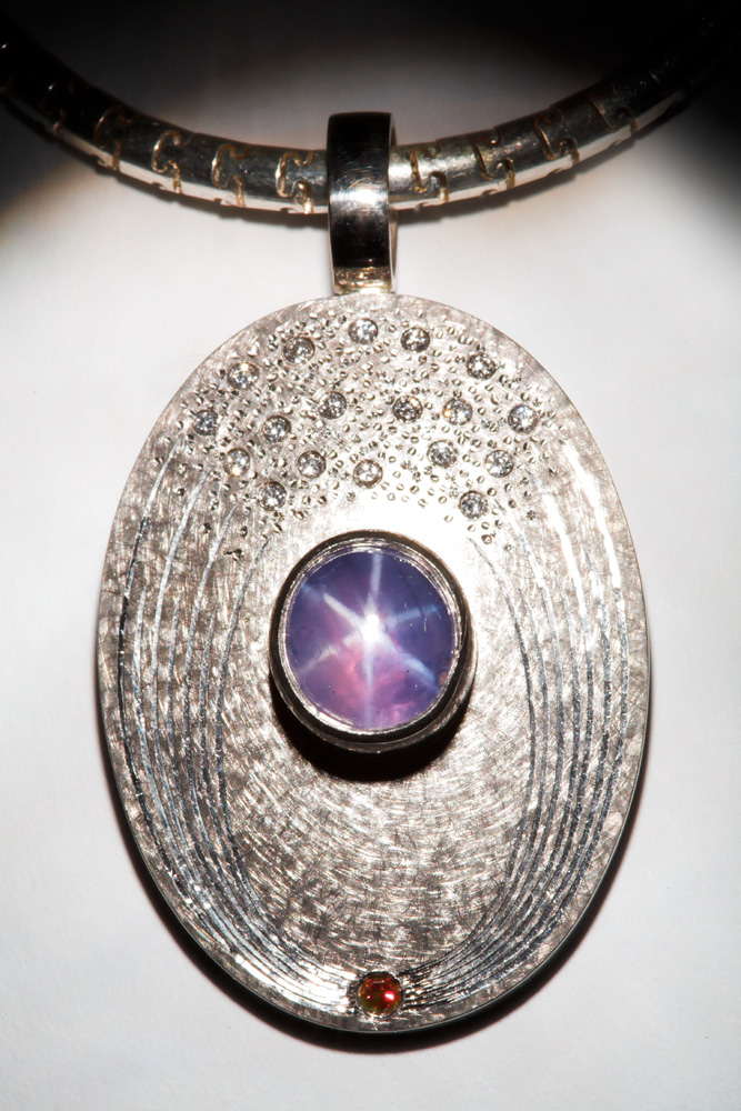 18ct white gold, 18 white diamonds and 1 pink diamond, oval pink star sapphire. Silver puzzle chain. 4.3cm high x 2.5cm wide. Photo Simon B Armitt