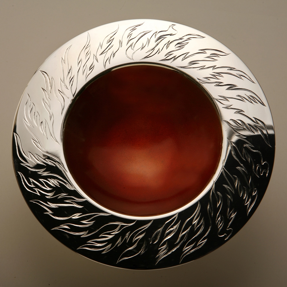 <a href="/jewellery/elements-spinning-bowl-fire-150mm-diam-brittania-silver-hand-engraved-orange-enamel-photo">ELEMENTS SPINNING BOWL - FIRE 150mm diam. Brittania Silver, Hand Engraved, Orange enamel. Photo Andra Nelki</a>