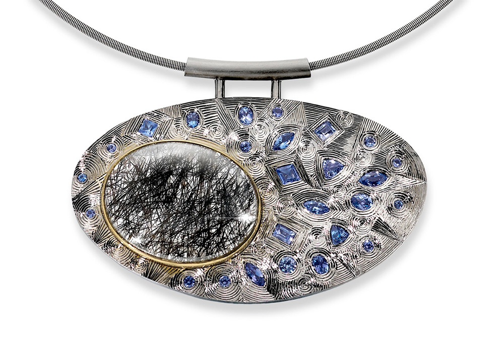Silver finished in grey rhodium, hand engraved, set with various shaped tanzanites and oval rutilated quartz set in yellow gold. Stainless steel neck chain.Photo: Simon B Armitt